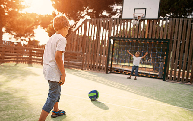 Dois rapazes a jogar à bola num parque