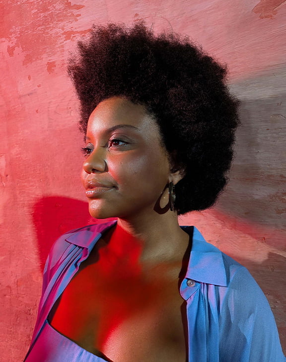 Imagem de estilo de vida de uma mulher encostada a uma parede, sob iluminação vermelha.