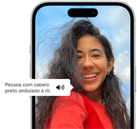 iPhone 15 com a funcionalidade VoiceOver a descrever a imagem: uma pessoa de cabelo preto ondulado a rir
